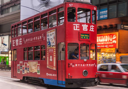 Hong Kong Island, China  - May 14, 2010: Des Voeux Road Central. Red streetcar features several advertisements. Street scene with car and people.のeditorial素材