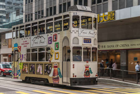 Hong Kong Island, China  - May 14, 2010: Des Voeux Road Central. White streetcar features advertisement for Fionaâs Prince children shoesk showing shoes and childrenâs toys.  Street scene with  people.のeditorial素材