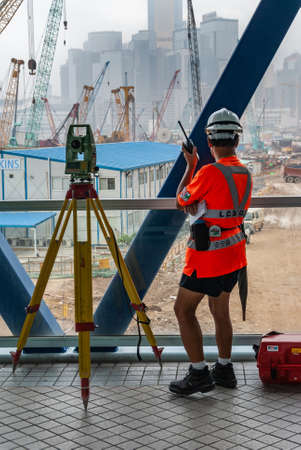 Hong Kong Island, China  - May 14, 2010: Surveyor with mounted scope and communication equipment overlooks construction site near 2IFC. Highrises and plenty of cranes.のeditorial素材