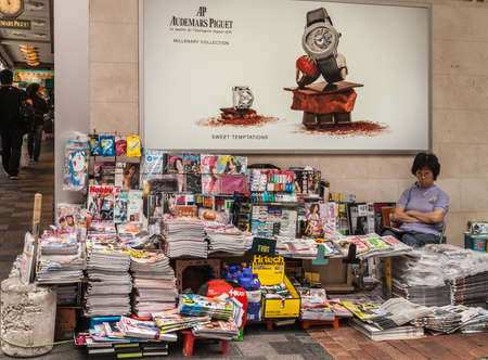 Hong Kong, China  - May 13, 2010: Newspaper and Magazine and magazine stand shop with merchant present along Nathan Road in Kowloon under sign for Audemars Paguet watch.のeditorial素材
