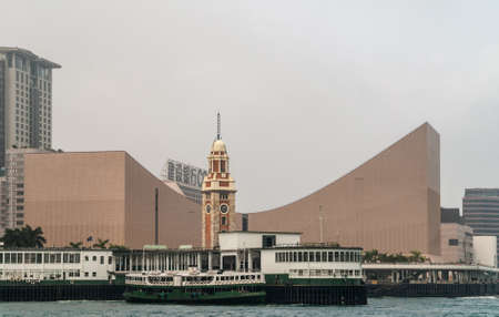 Hong Kong, China  - May 12, 2010: Former Kowloon-Canton Railway Clock Tower in front of Cultural Center and behind ferry docks of Kowloon at Victoria Harbour. Silver sky.のeditorial素材