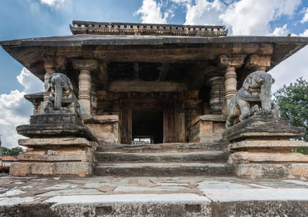 Belavadi, Karnataka, India - November 2, 2013: Veera Narayana Temple. Entrance hall, street side, to the sanctuary grounds show two elephant statues and a pillared structure. Blue sky with white clouds.の写真素材