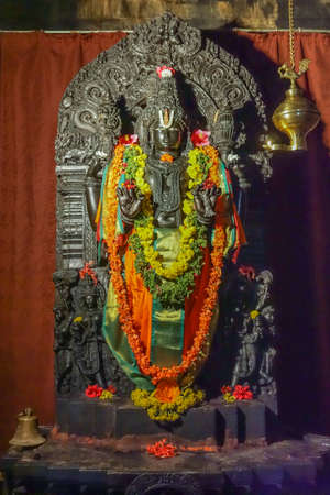 Belavadi, Karnataka, India - November 2, 2013: Veera Narayana Temple. Tall most important Narayana statue of Vishnu in shrine. Colorfully decorated with flowers and ribbons, offsetting dark metal sculpture.のeditorial素材