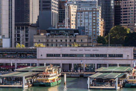 Sydney, Australia - February 12, 2019: Closeup of Ferry terminal and Circular Quay Railway Station. Hightrises in back. Ferries in action. Evening shot with sun falling on boat.のeditorial素材