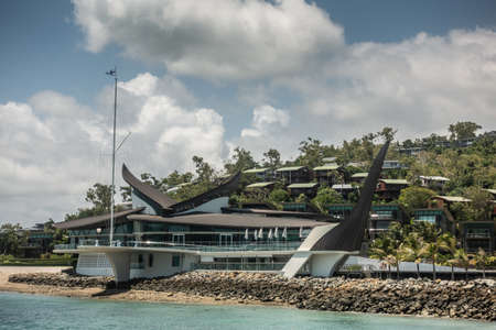 Hamilton Island, Australia - February 16, 2019: Black and white Iconic Yacht Club House, shot from sea, under blue sky and white cloudscape.のeditorial素材