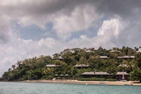 Hamilton Island, Australia - February 16, 2019: Villas as Upscale Qualia Beacht Resort  with private beach, built on green hill overlooking the coral sea. Blue sky with dark cloudscape.のeditorial素材
