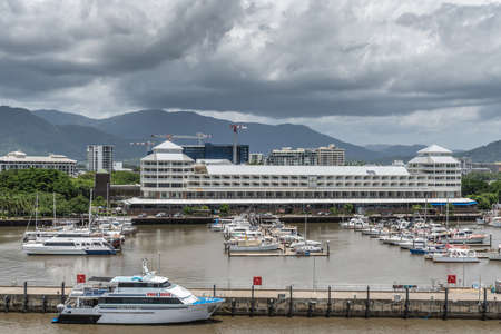 Cairns, Australia - February 17, 2019: Shangri-La Hotel at the yacht harbor with many boats under rainy sky with Kuranda National Park mountains in back.のeditorial素材