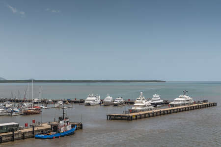Cairns, Australia - February 17, 2019: Yacht harbor entrance with many boats and Coral Sea in back under light blue sky.のeditorial素材