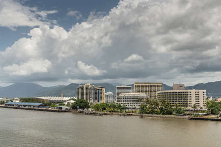 Cairns, Australia - February 17, 2019: Cruise terminal, Convention center, Hilton hotel and Pullman Hotel Casino under cloudscape with Kuranda National Park mountains in back. Chinaman Creek in front.のeditorial素材