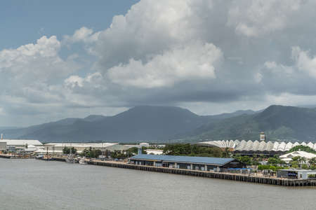 Cairns, Australia - February 17, 2019: Cruise Liner Terminal with convention center in back. Further up Chinaman Creek, industrial warehouses. Kuranda National Park mountains under cloudscape.のeditorial素材