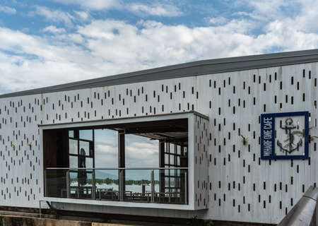 Cairns, Australia - February 17, 2019: Wharf One Cafe facade and window with anchor logo. âChinaman Creekâ with sailing yachts visible through window.のeditorial素材
