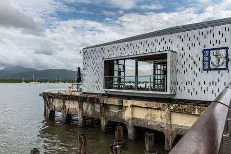 Cairns, Australia - February 17, 2019: Wharf One Cafe facade and window with anchor logo over water of âChinaman Creekâ with sailing yachts. Blue sky with white cloudscape.のeditorial素材