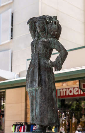 Darwin Australia - February 22, 2019: Closeup of The bronze Water Bearer statue on the mall downtown, created by sculptor Irene Kokkinos. Commercial street scene with faded shop in back.のeditorial素材