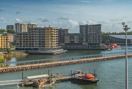 Darwin Australia - February 22, 2019: Wharf One residential and retail business buildings on pontons in the harbour. Long walkway bridge and Convention Center roof on right. Under morning cloudscape.のeditorial素材