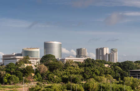 Darwin Australia - February 22, 2019: South side office towers in downtown behind green zone holding Government House bordering harbour under blue sky.のeditorial素材