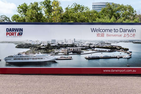 Darwin Australia - February 22, 2019: large mural welcome multi-lingual photo sign in the port with green foliage peeping over the wall.  Downtown, the harbour and cruise ship.のeditorial素材