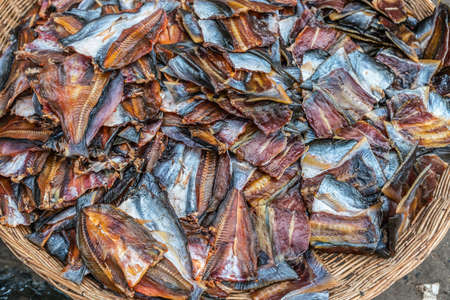 Sihanoukville, Cambodia - March 15, 2019: Phsar Leu Market. Closeup of brown basket filled with dried and smoked pieces of fish in brown, blue and red colors.のeditorial素材