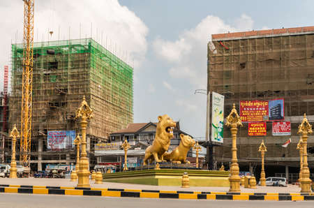 Sihanoukville, Cambodia - March 15, 2019: Golden Lions Roundabout. Wider shot of west flank of giant statues of the beasts. Lanterns, Construction sites in back.のeditorial素材