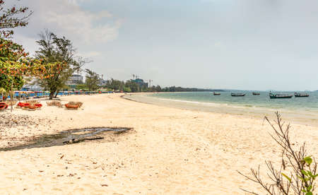 Sihanoukville, Cambodia - March 15, 2019: Wide shot of sandy Ochheuteal Beach with boats on the sea, chairs on the sand and construction sites at the horizon.のeditorial素材