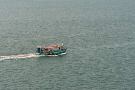 Sihanoukville, Cambodia - March 15, 2019: Closeup of Small wooden ferry and supply boat near Sihanoukville Autonomous Port sailing on greenish sea water.のeditorial素材