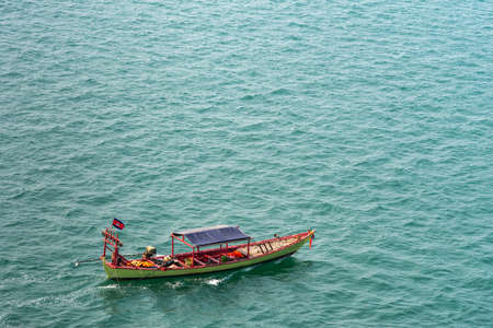 Sihanoukville, Cambodia - March 15, 2019: Small green and red fishing sloop on greenish sea water outside Sihanouk Autonomous Port.のeditorial素材