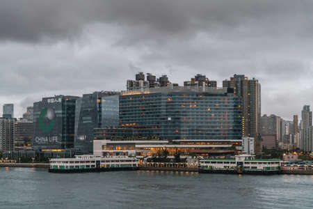 Hong Kong, China - March 7, 2019: Very early morning under dark rainy sky. Kowloon Bay, skyline at Kerry Hotel neighborhood with tall buildings and white Hung Hom ferry facilities at shore.のeditorial素材