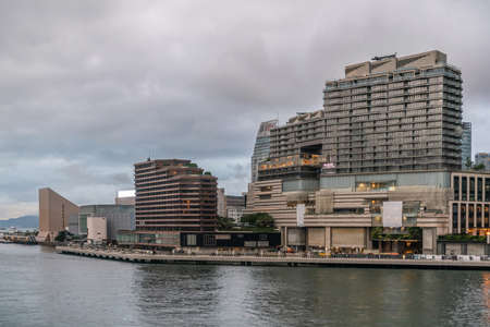 Hong Kong, China - March 7, 2019: Very early morning under dark rainy sky. Kowloon skyline behind Avenue of the Stars at Victoria harbour.のeditorial素材