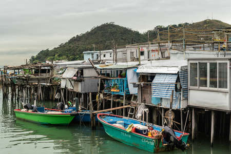 Hong Kong, China - March 7, 2019: Tai O Fishing village. White Poor Fishermen houses on stilts at Tai O River mouth  Color added by sloops, buoys and tarps. Chaotic picのeditorial素材