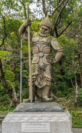 Hong Kong, China - March 7, 2019: Lantau Island. Po Lin Buddhist Monastery. Stone statue of General Indra, one of the twelve Divine Generals. Green foliage background.のeditorial素材