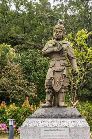 Hong Kong, China - March 7, 2019: Lantau Island. Po Lin Buddhist Monastery. Stone statue of General Anila, one of the twelve Divine Generals. Green foliage background.のeditorial素材