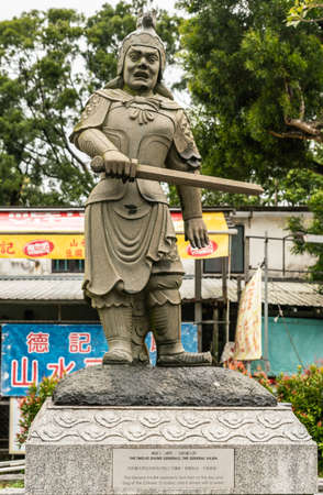 Hong Kong, China - March 7, 2019: Lantau Island. Po Lin Buddhist Monastery. Stone statue of General Vajra, one of the twelve Divine Generals. Yellow, blue and red background of retail store.のeditorial素材