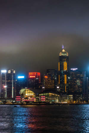 Hong Kong, China - March 7, 2019: Convention Center Hong Kong Island skyline during rainy night. Color lights on buildings, reflections in water of Victoria Harbour, traffic on water.のeditorial素材
