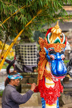 Bali, Indonesia - February 25, 2019: Ulun Danu Beratan Temple complex in Bedoegoel. Closeup, Man paints a water dragon in vivid colors. Green foliage.のeditorial素材