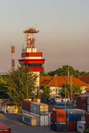 Benoa Harbour, Bali, Indonesia - February 26, 2019: Communications and control tower at sunrise surrounded by containers and office buildings.のeditorial素材