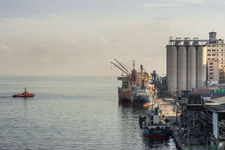 Makassar, Sulawesi, Indonesia - February 28, 2019: Gray concrete cylindrical Silo towers with ships loading in the port.のeditorial素材