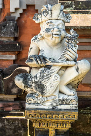 Klungkung, Bali, Indonesia - February 26, 2019: Closeup of white statue of violin player at Royal Palace. Black mold on statue and stone behind of red bricks.のeditorial素材