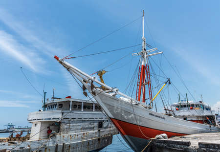 Makassar, Sulawesi, Indonesia - February 28, 2019: Paotere Old Port. Red and white Bunga Asmara Sejati island tranport boat docked and seen from bow under blue sky.のeditorial素材