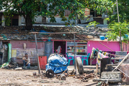 Makassar, Sulawesi, Indonesia - February 28, 2019: Paotere Old Port. Store on side of harbor sells basic food and drinks to dock workers. Chaotic sight around with trash and filth. Green foliage on top.のeditorial素材