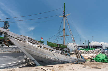 Makassar, Sulawesi, Indonesia - February 28, 2019: Paotere Old Port. White Amran Berkembang island transport boat almost fully loaded with bags sits at dock under blue sky.のeditorial素材