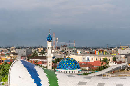 Makassar, Sulawesi, Indonesia - February 28, 2019: Evening closeup on cruise ship terminal with Masjid Babulssalam Pelabuhan mosque and city skyline. Rain storn approaching cloudscape.のeditorial素材