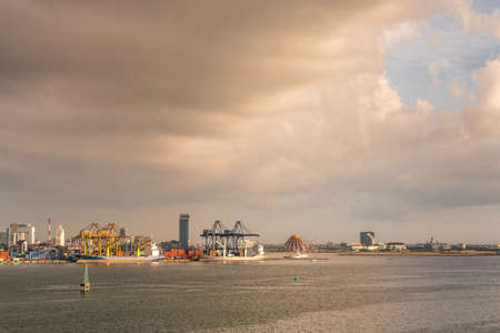 Makassar, Sulawesi, Indonesia - February 28, 2019: Evening wide shot of container terminal. On horizon city buildings and beehive Masjid Raya Sulawesi Selatan under cloudscape.のeditorial素材