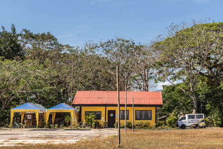 Puerto Princesa, Palawan, Philippines - March 3, 2019: Iwahig Penal Colony. Yellow security office with red roof and small rescue van on the side. Green foliage and blue sky.のeditorial素材