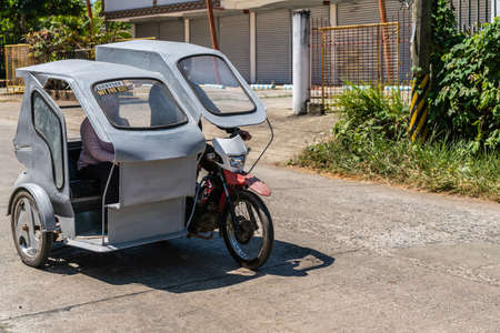 Puerto Princesa, Palawan, Philippines - March 3, 2019: Street view. Simple gray taxi motor-tricycle...