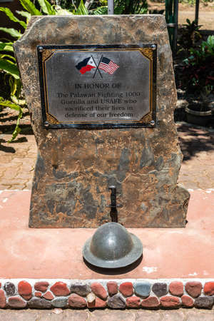 Puerto Princesa, Palawan, Philippines - March 3, 2019: Brown stone with plate memorizing the Guerillas and USAFE fighters who died in defense of freedom. Some green vegetation in back.のeditorial素材