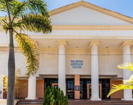 Puerto Princesa, Palawan, Philippines - March 3, 2019: Entrance of Palawan Heritage Center beige colored building under blue sky. Green palm in front.のeditorial素材