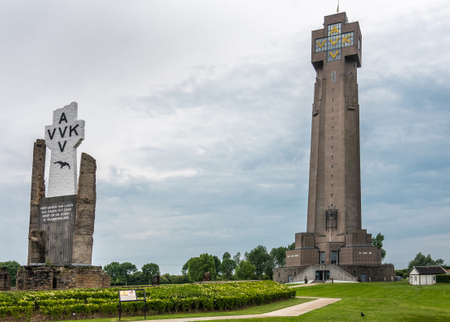 Diksmuide, Flanders, Belgium -  June 19, 2019: Black on White Crypt memorial, remnants of dynamited tower, and new IJzertoren, tallest peace monument of WW 1 against gray cloudscape.のeditorial素材
