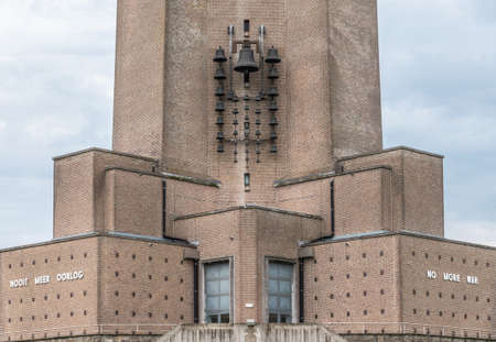 Diksmuide, Flanders, Belgium -  June 19, 2019: Foot of medestal of IJzertoren, tallest peace monument of WW 1. Text read No More War in Dutch and English. Carilon on brick wall.のeditorial素材