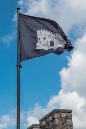 Gent, Flanders, Belgium -  June 21, 2019: Closeup of black-white flag of Gravensteen on top of castle tower against white cloudscape with blue patches.のeditorial素材