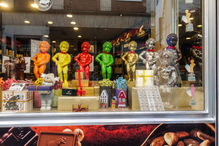 Brussels, Belgium - June 22, 2019: Large chocolate Manneken Pis statues in different colors posing on top of collection of chocolat gifts in window of confectionery store.のeditorial素材