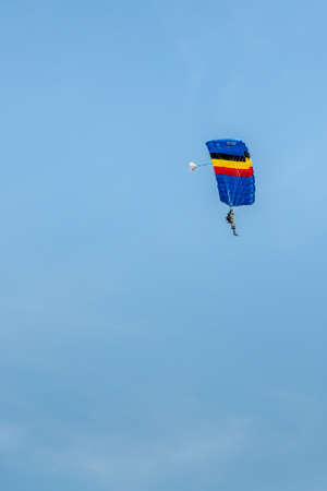 Han-sur-Lesse, Belgium - June 25, 2019: Belgian soldier on parachute with Belgian flag colors against blue sky.のeditorial素材